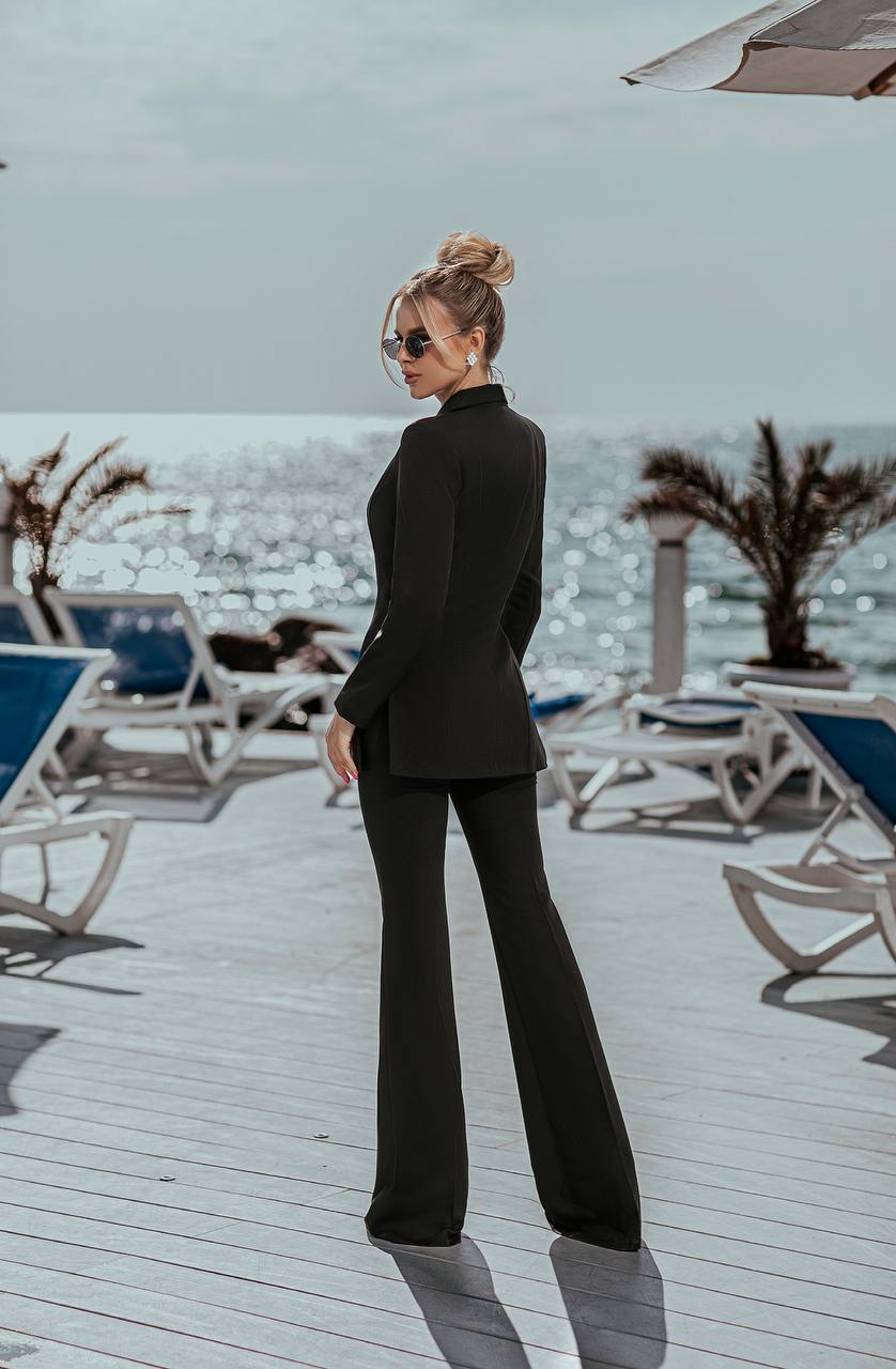 Woman in a black outfit standing on a deck with ocean view