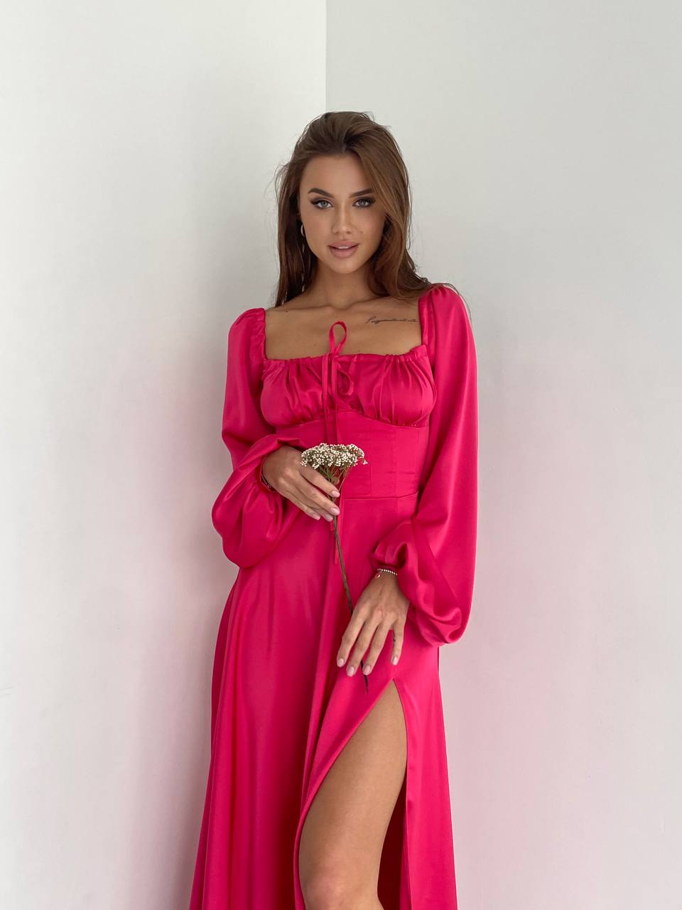 Woman wearing a pink dress with a high slit on a white background