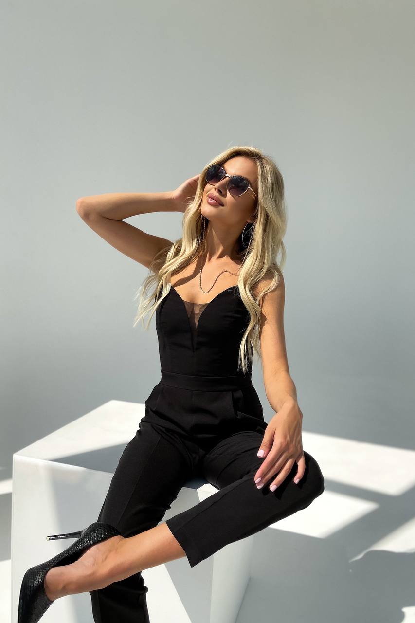 Woman in a black outfit sitting on a white chair against a light gray background