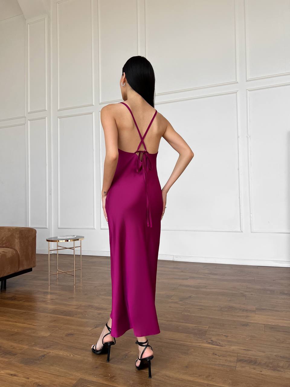 Woman wearing a magenta slip dress in a minimalistic room.