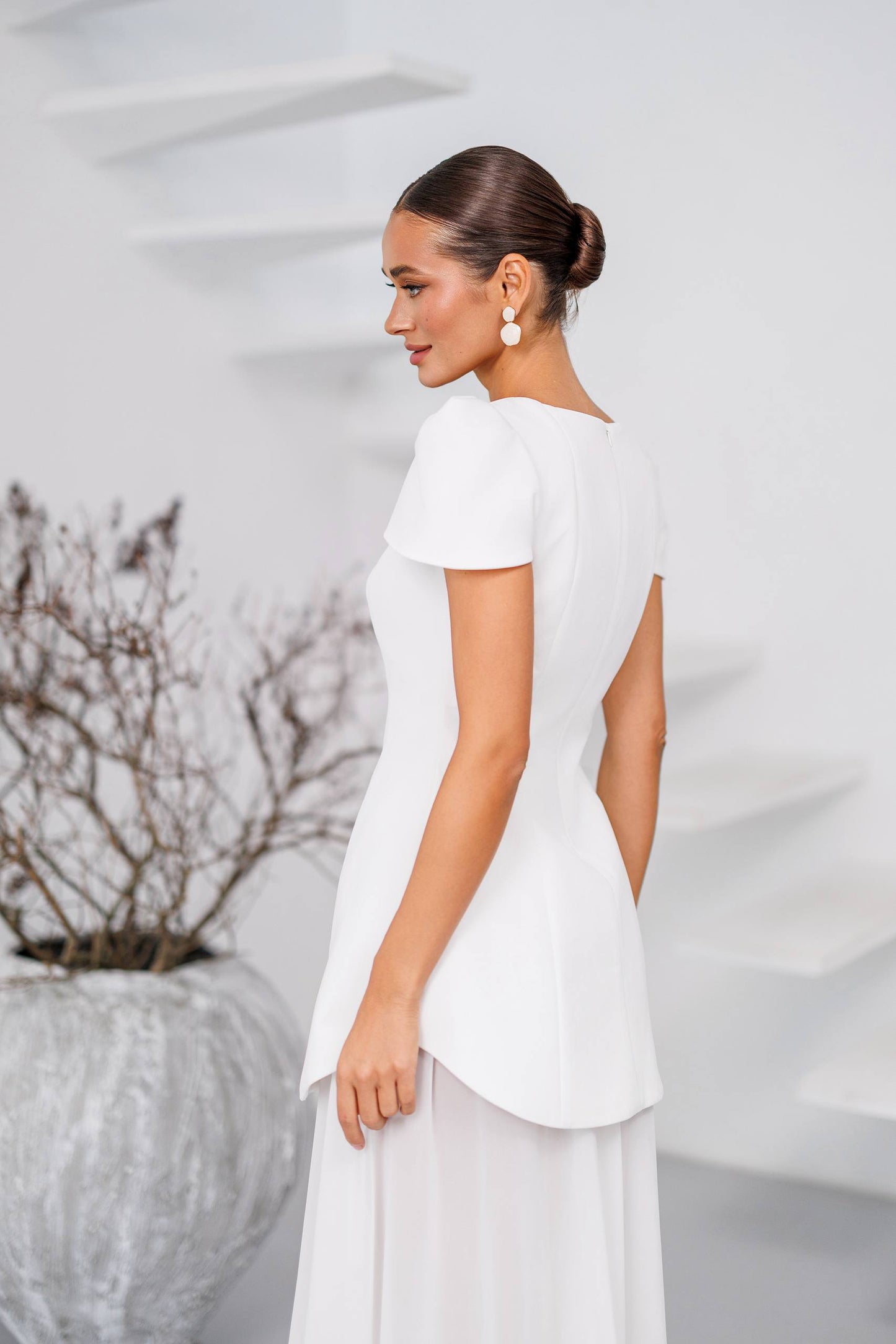 Woman wearing a white dress against a light gray background