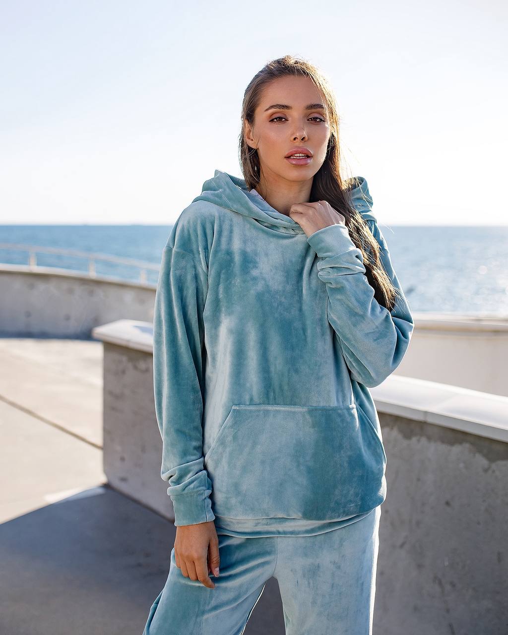 Woman wearing a light blue hoodie and pants by the ocean