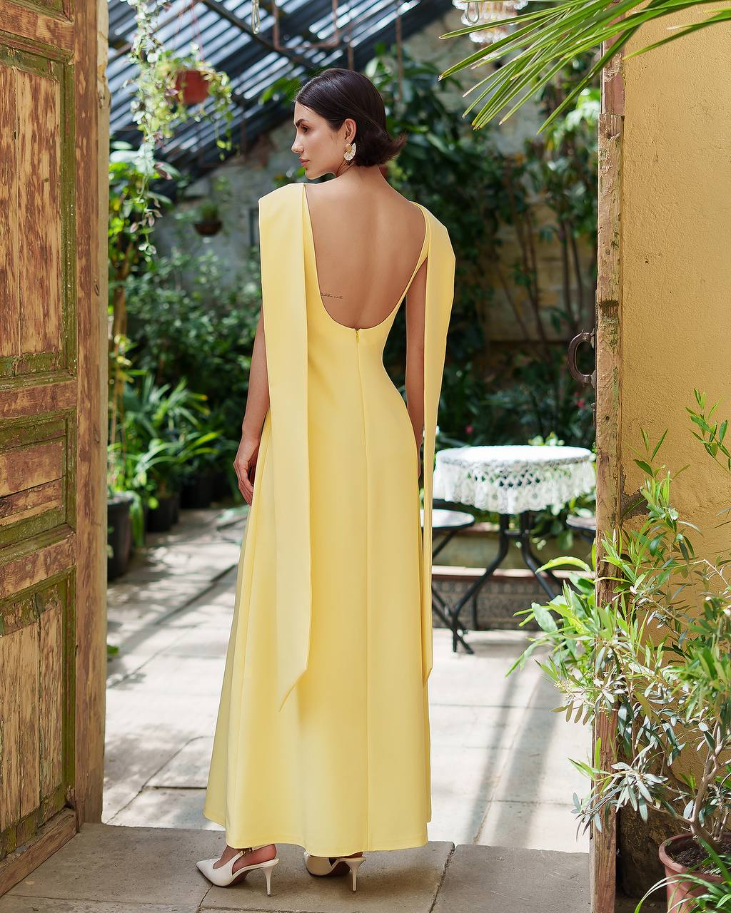 Woman in a yellow dress standing in a garden setting