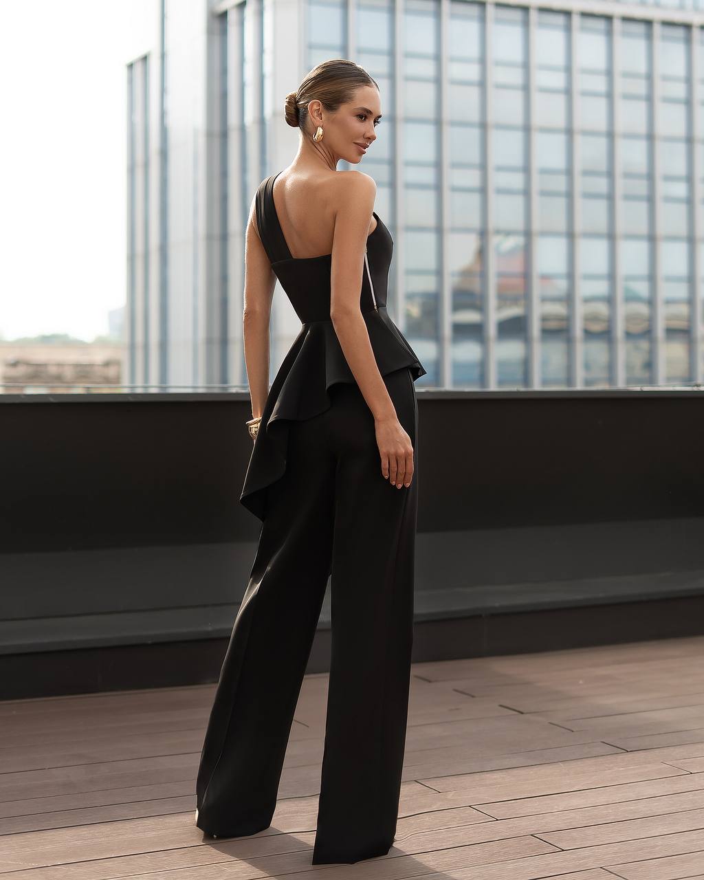 Woman in a black outfit standing on a rooftop with cityscape background