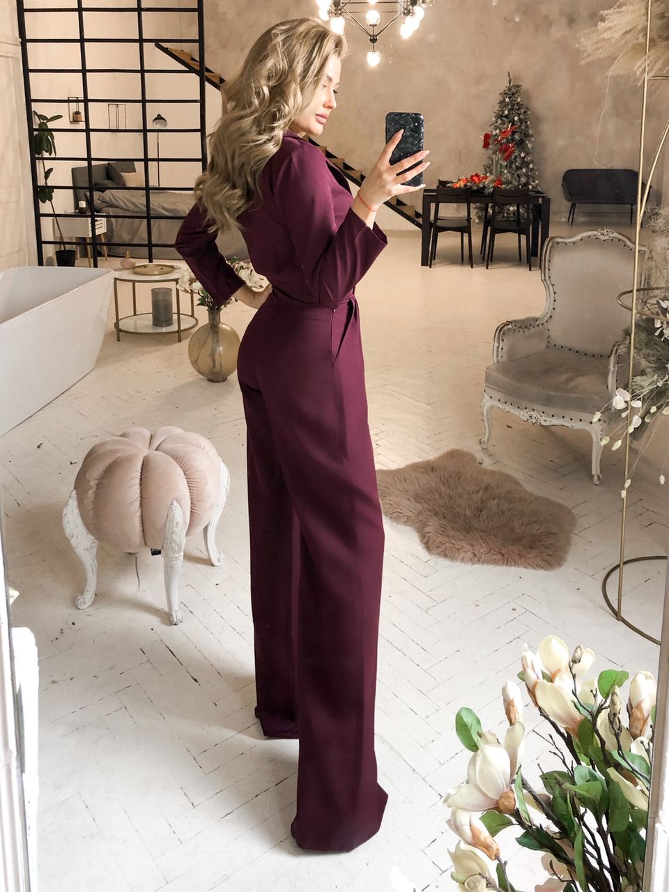 Woman in a purple dress taking a mirror selfie in a stylish room with decor elements.