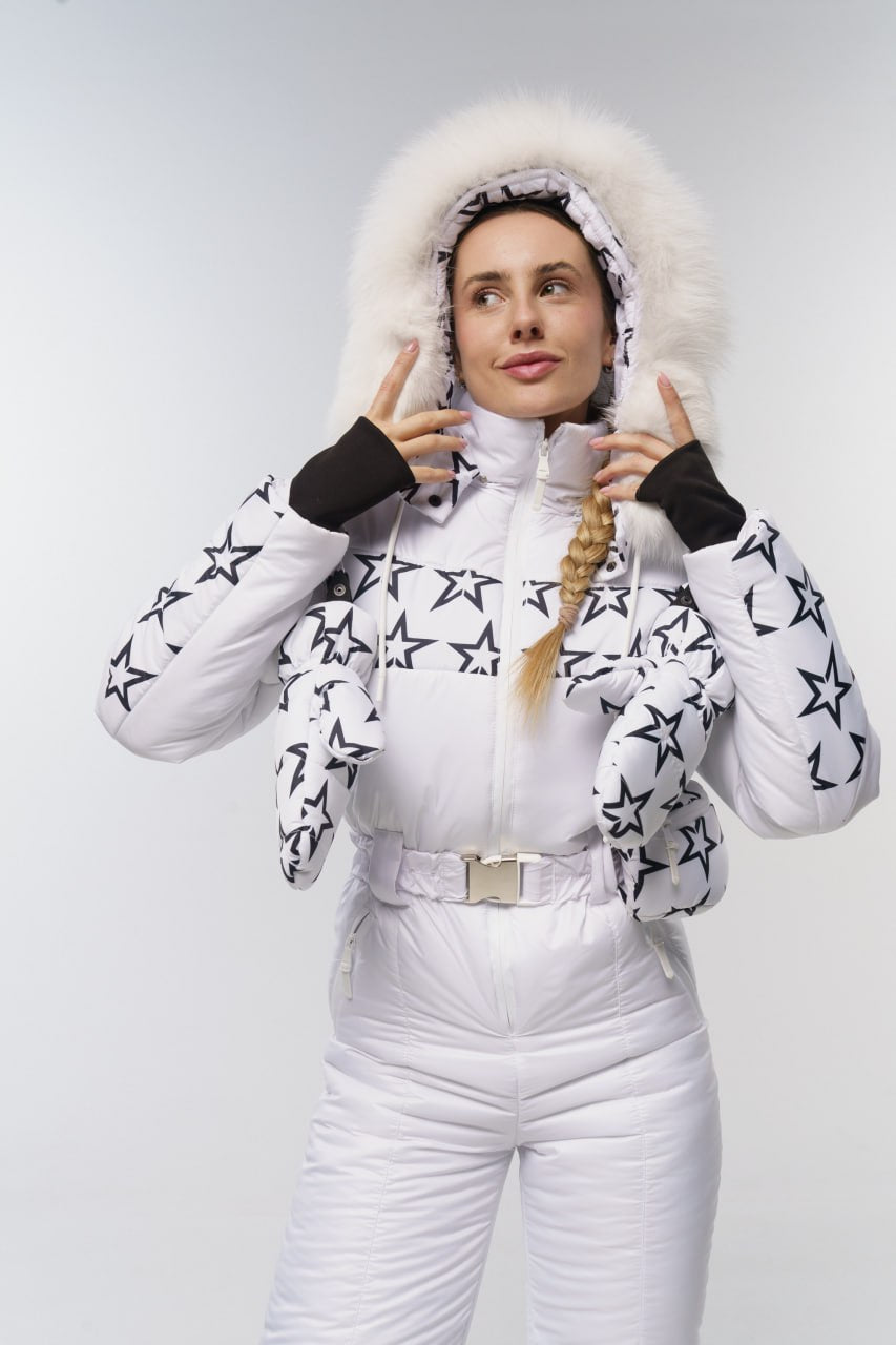 Woman wearing a white puffer jacket with star patterns and white pants on a light gray background