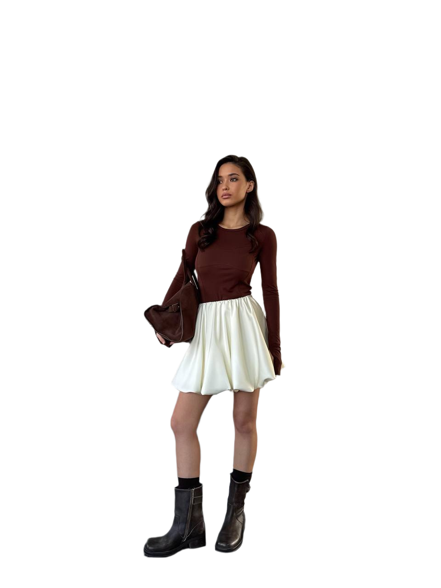 Woman wearing a brown top, white skirt, and black boots on a white background