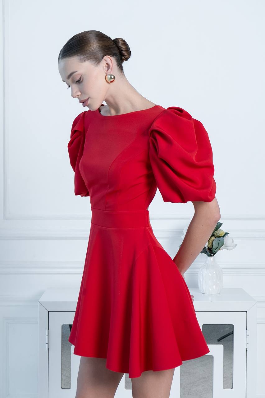 Woman wearing a red dress with puff sleeves against a white background