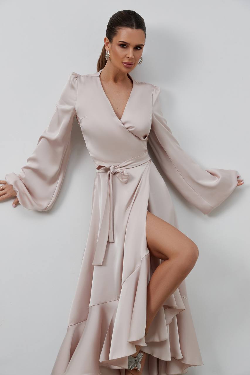 Woman wearing a light pink dress with long sleeves and a slit on a white background