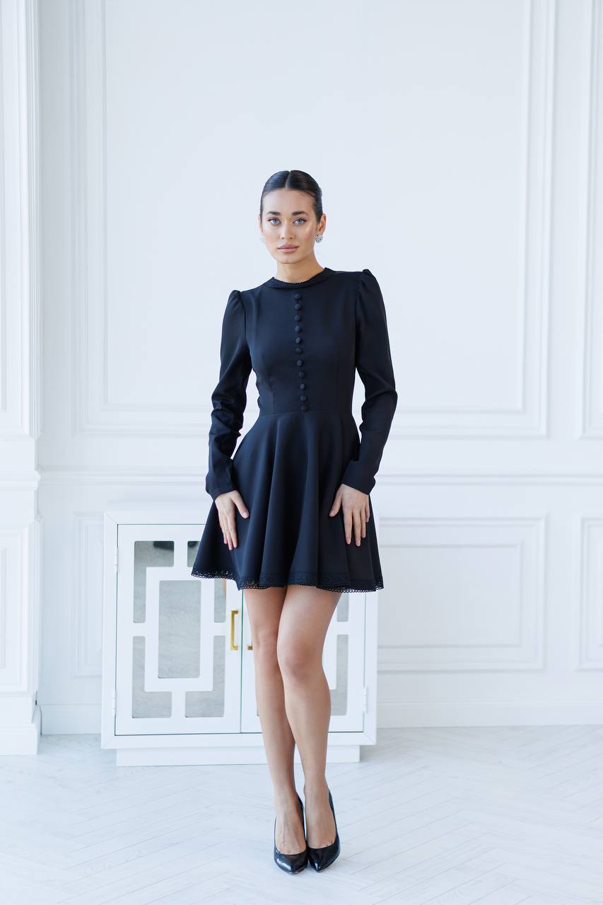 Woman wearing a black dress standing in a white room