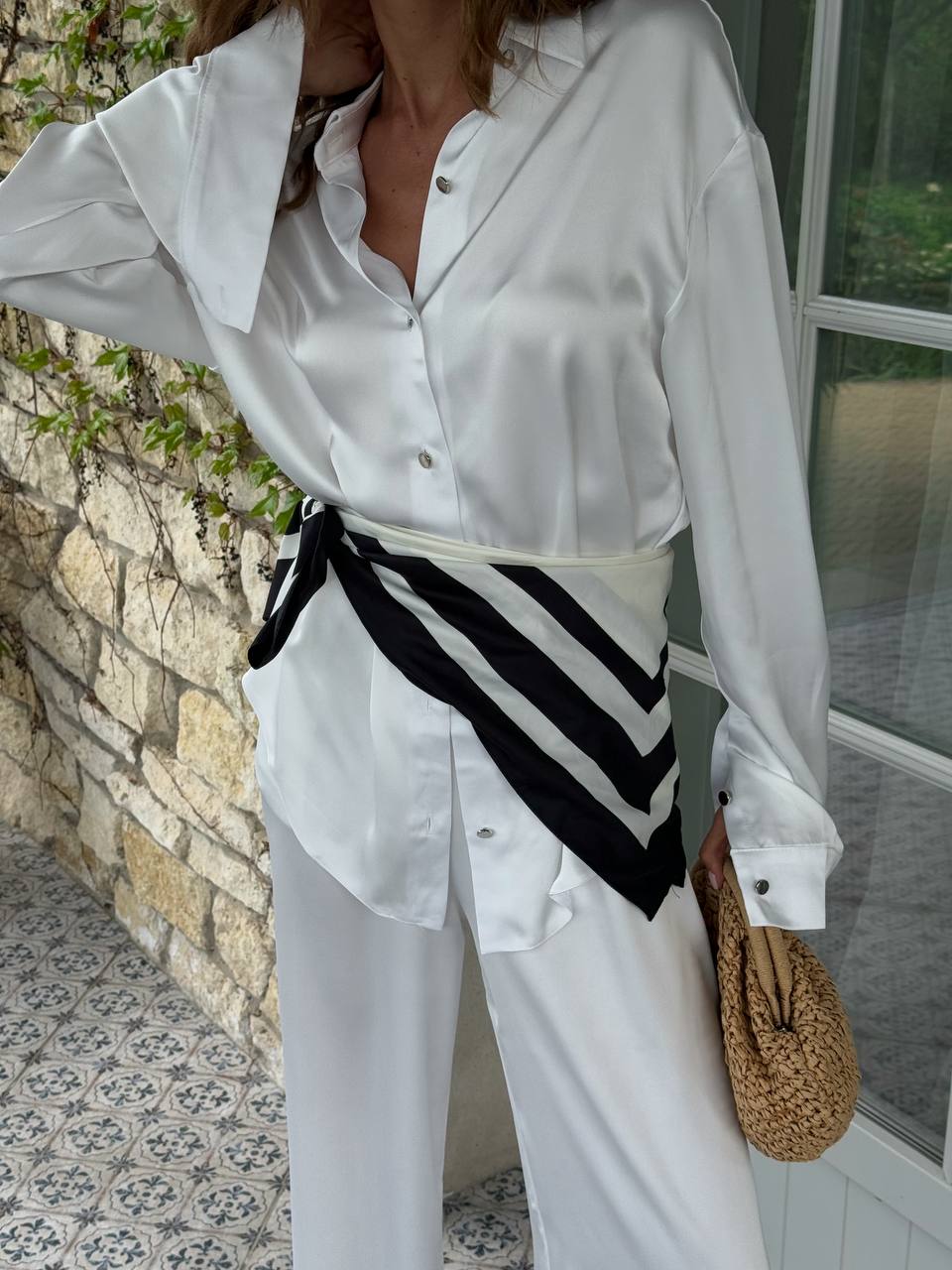 Person wearing a white shirt with a black and white striped tie, standing outdoors.