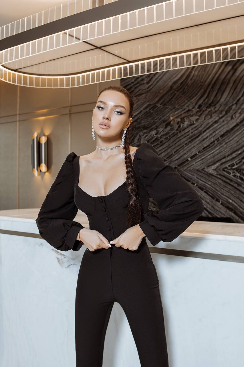 Woman in a black outfit posing in an elegant interior setting