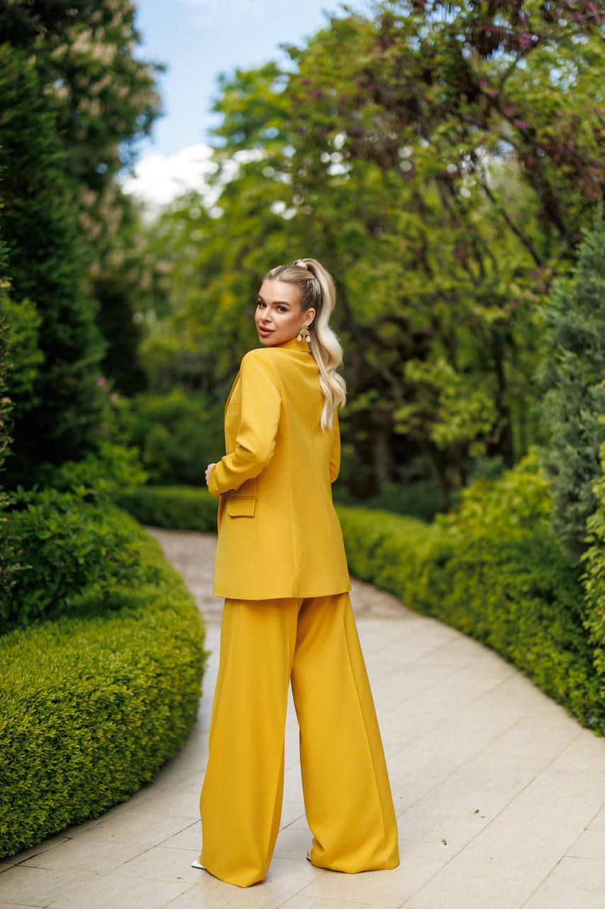 Woman in a yellow outfit standing on a path in a garden