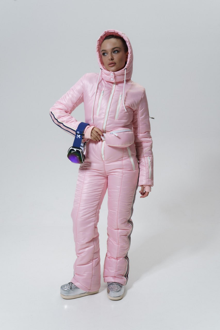 Person wearing a pink puffer suit holding goggles on a white background