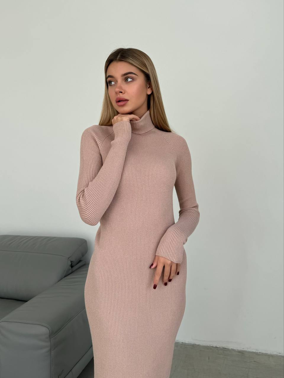 Woman wearing a long ribbed dress in a minimalistic room.