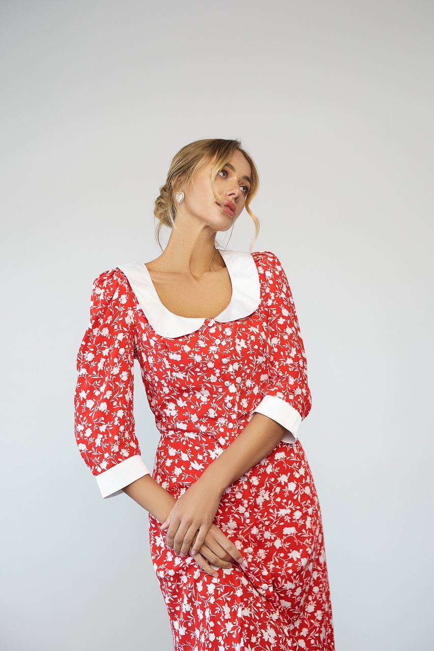 Woman wearing a red floral dress with white accents on a gray background