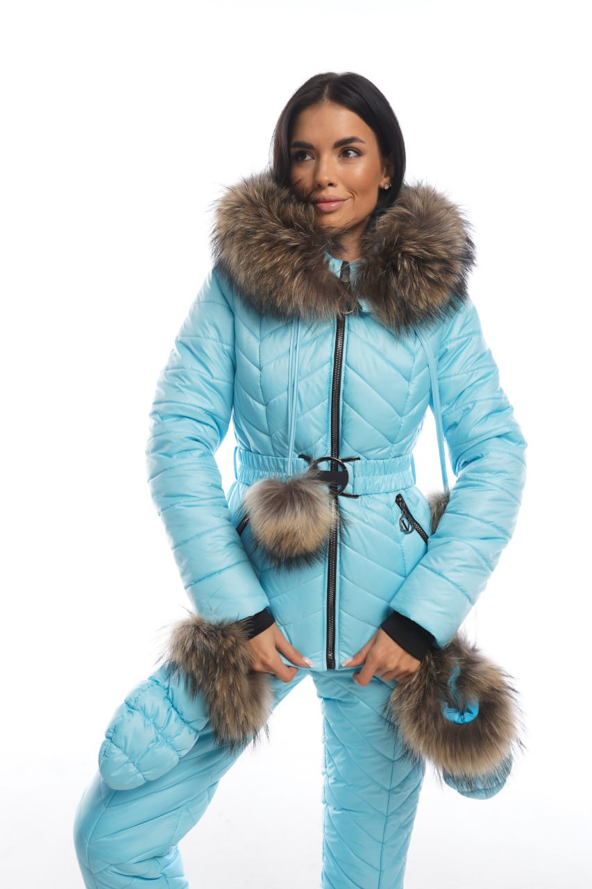 Woman wearing a light blue winter jumpsuit with fur trim on a white background