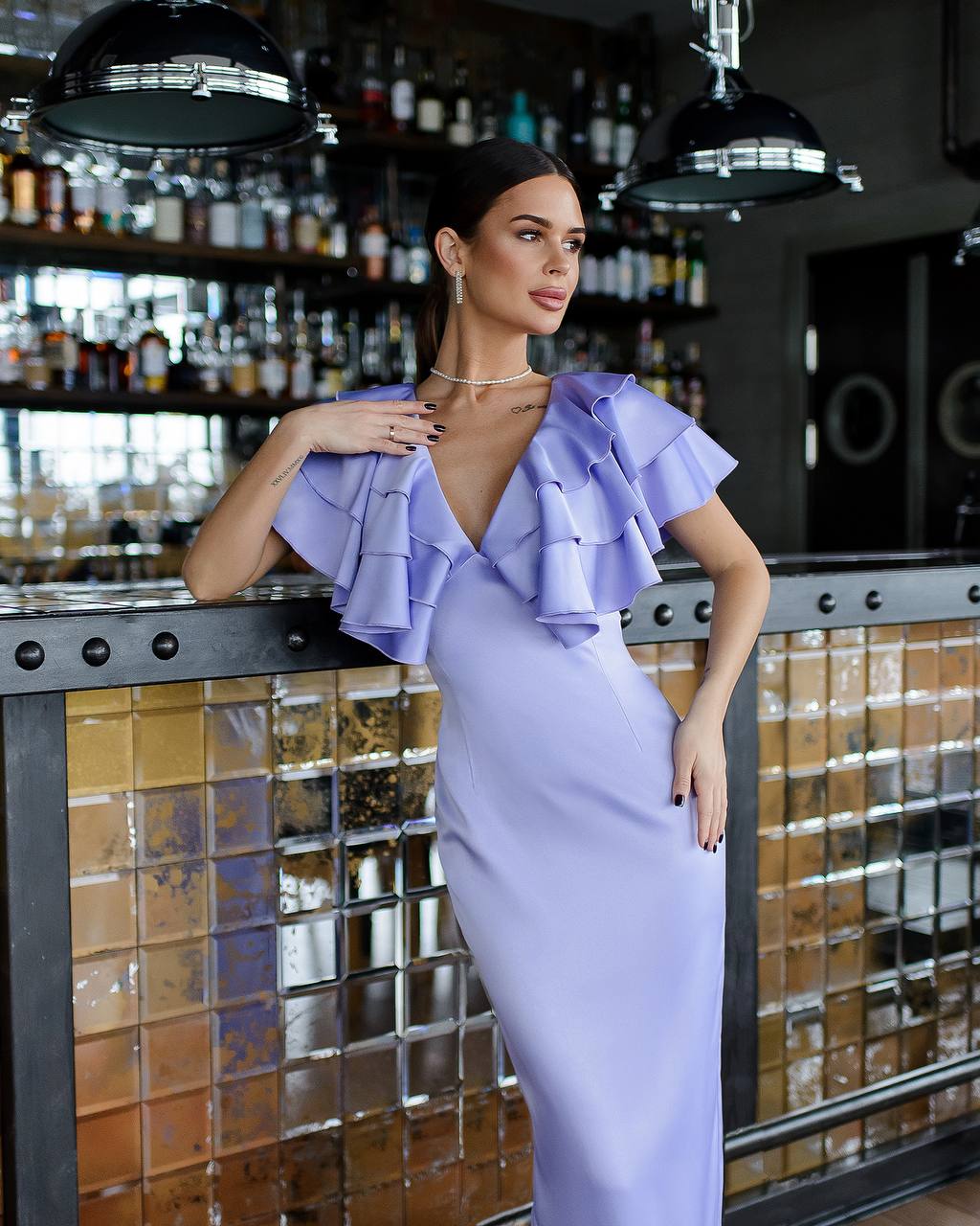 Woman in a lavender dress standing in a bar setting