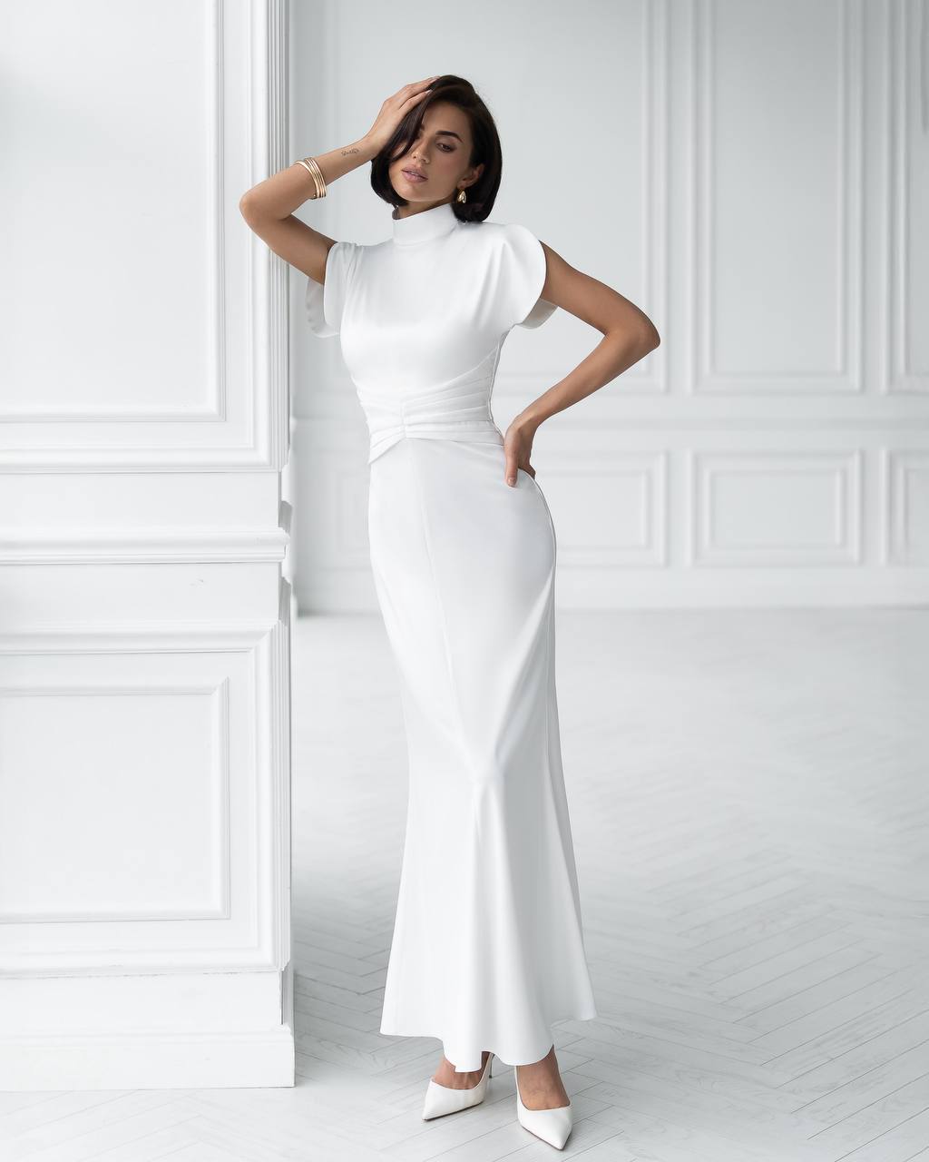 Woman wearing a white dress against a white wall