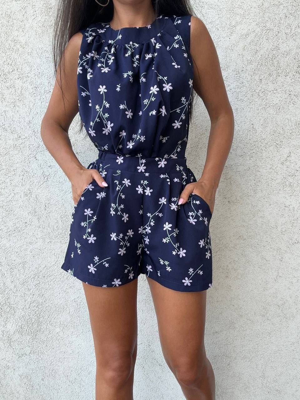 Navy blue floral romper worn by a person against a light gray background
