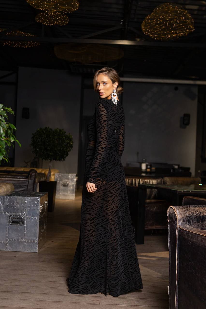 Woman in a black dress standing in an indoor setting with decor elements.