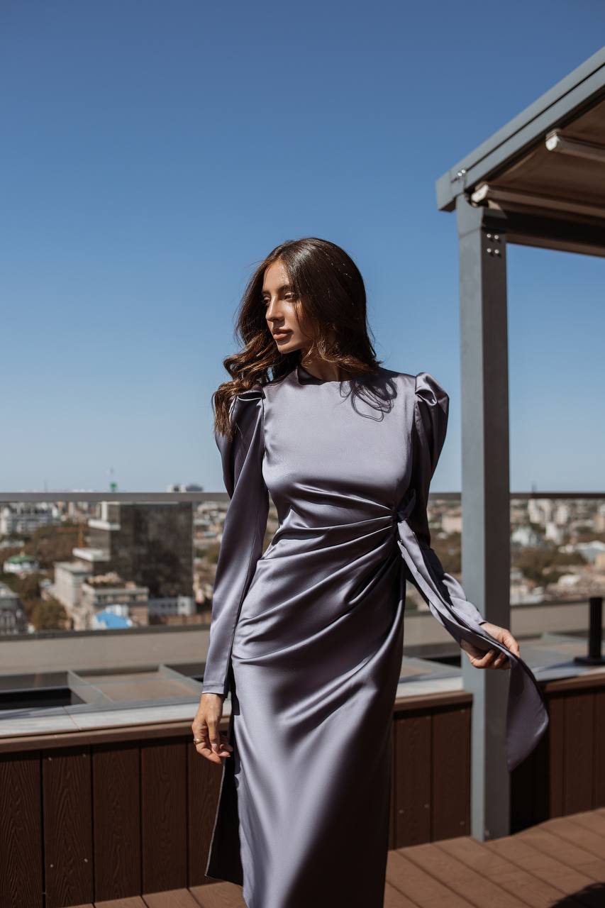 Woman in a gray dress standing on a rooftop with a cityscape in the background