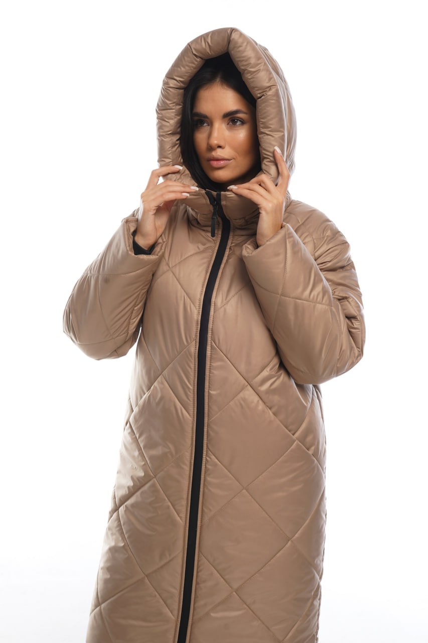 Woman wearing a beige quilted coat with a hood on a white background