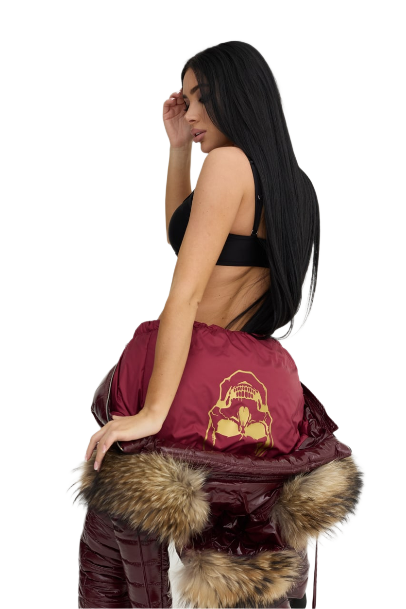 Woman holding a maroon bag with fur trim against a white background