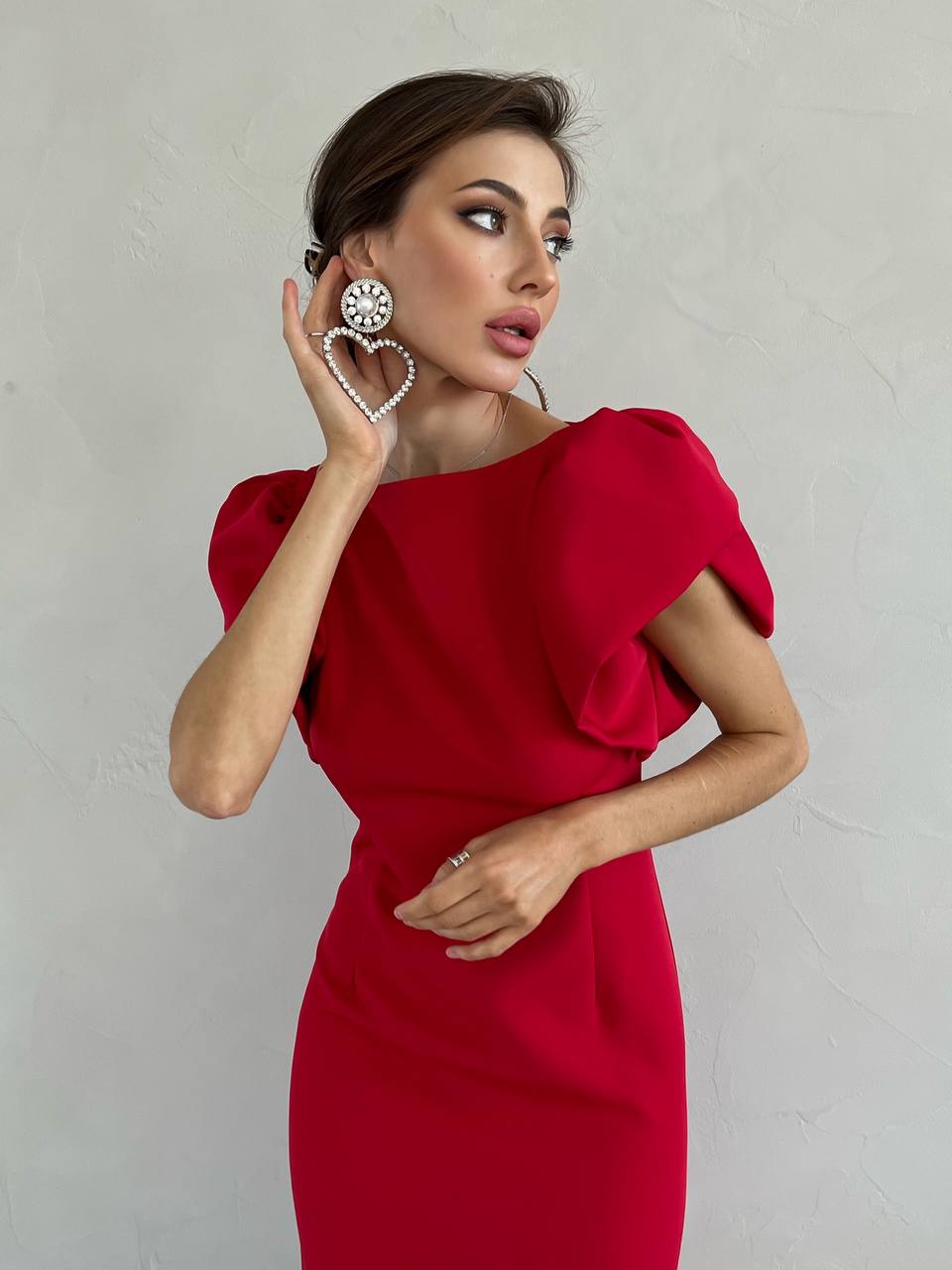 Woman wearing a red dress with puffed sleeves against a plain background