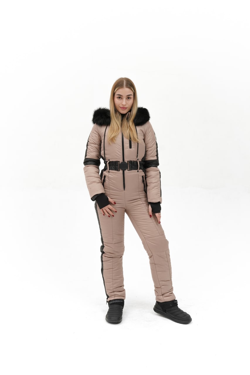 Woman wearing a beige snowsuit with black accents on a white background