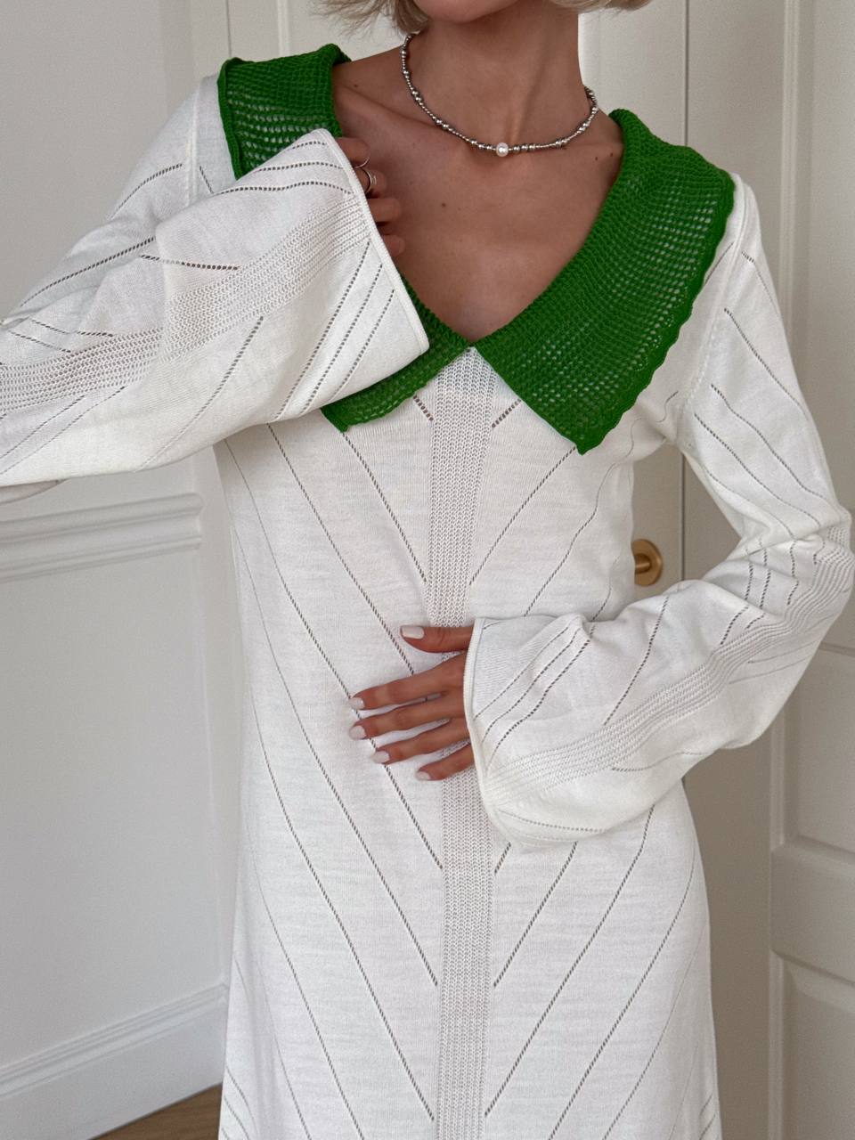 Person wearing a white and green dress with a textured pattern.