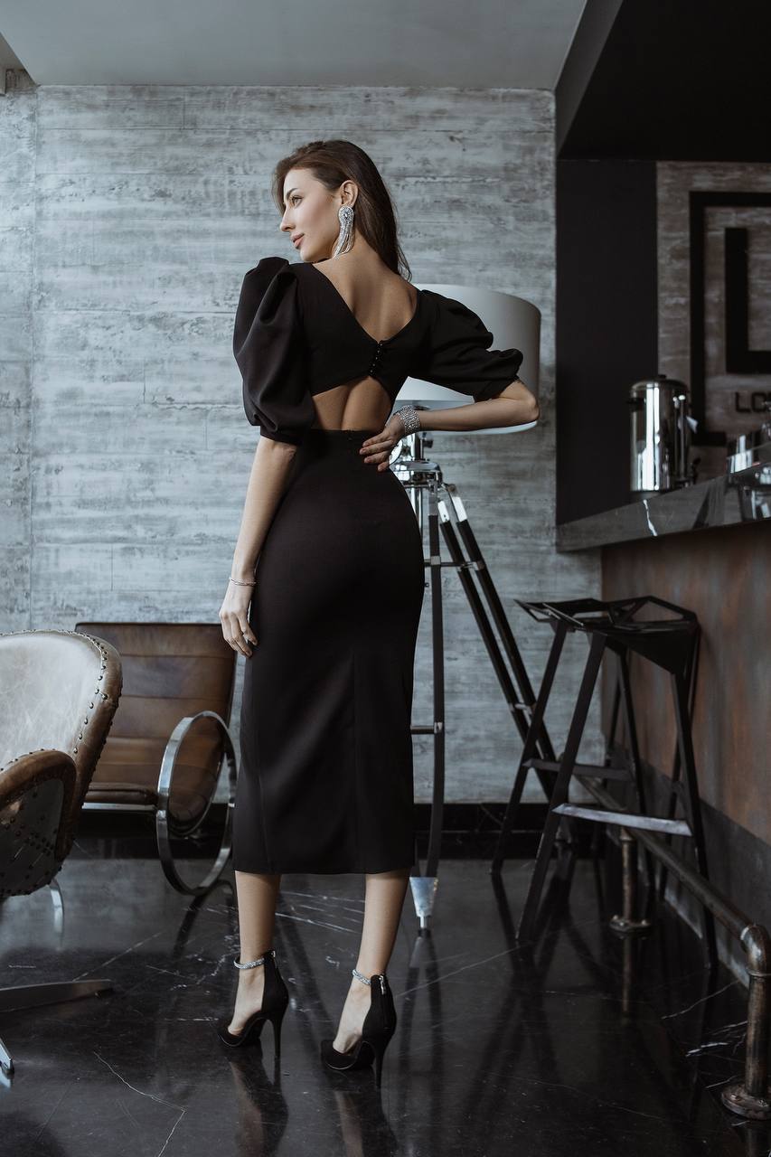 Woman in a black dress standing in a modern interior setting