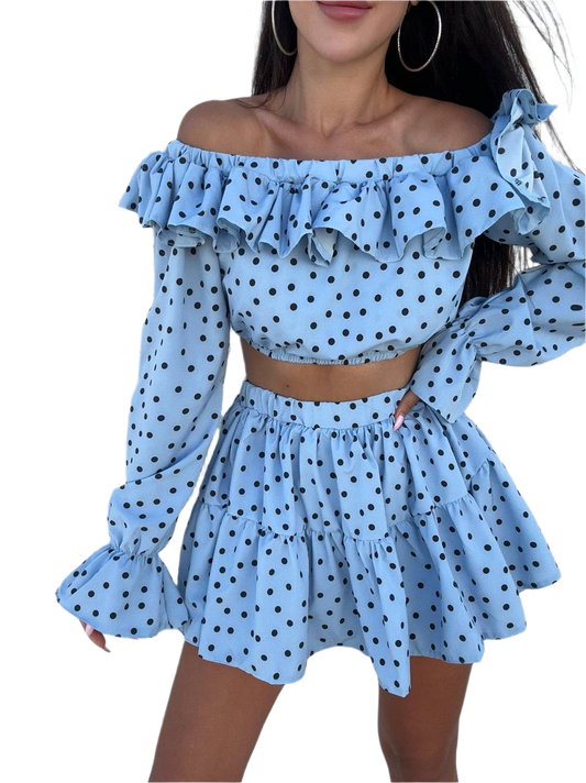 Woman wearing a blue polka dot off-shoulder top and skirt set on a white background
