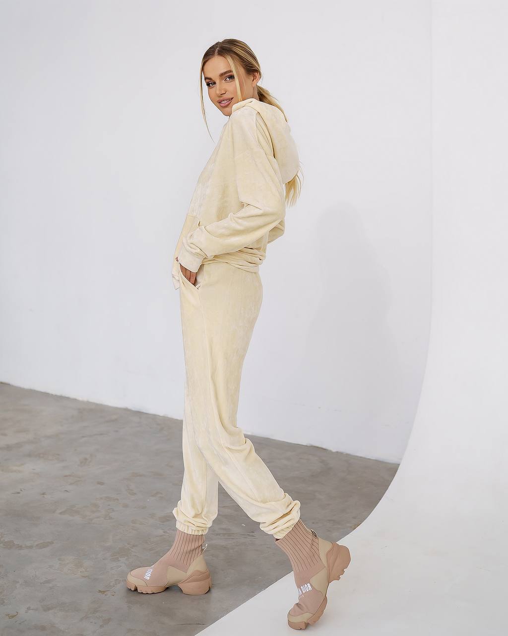 Woman wearing a beige tracksuit standing against a white background