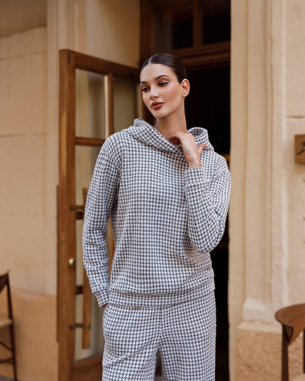 Woman wearing a houndstooth patterned outfit standing in a doorway.