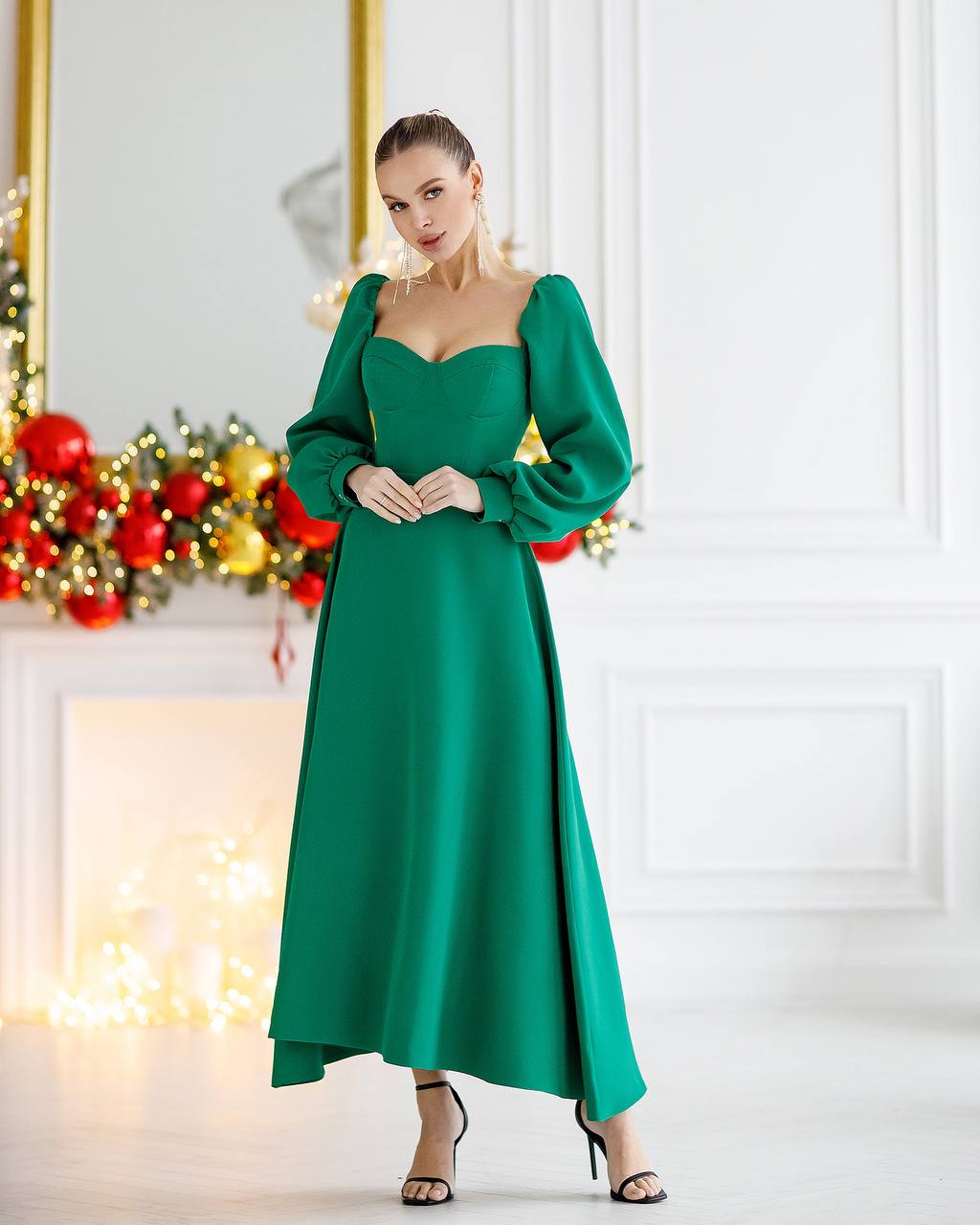 Woman wearing a green dress in a festive indoor setting with Christmas decorations.