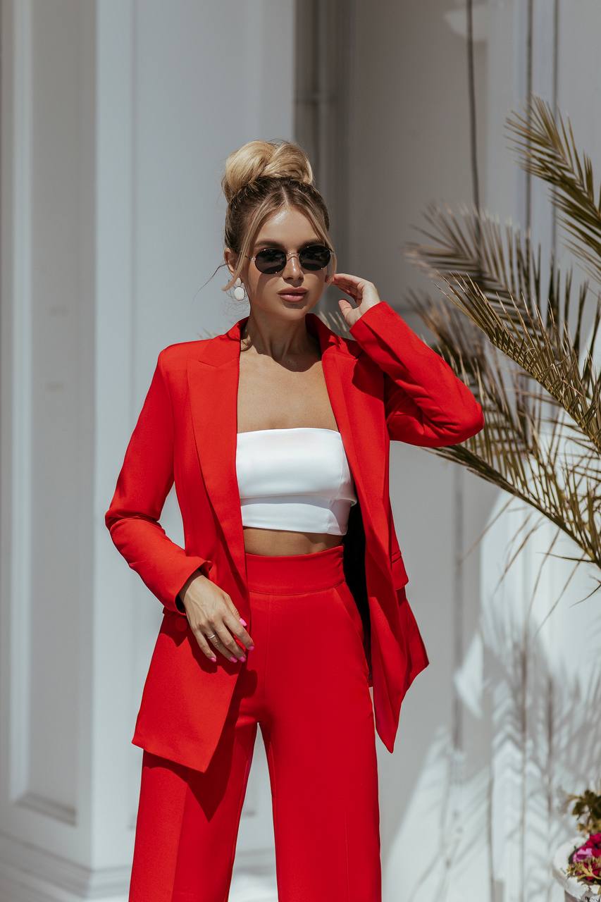 Woman wearing a red suit and white top in an outdoor setting