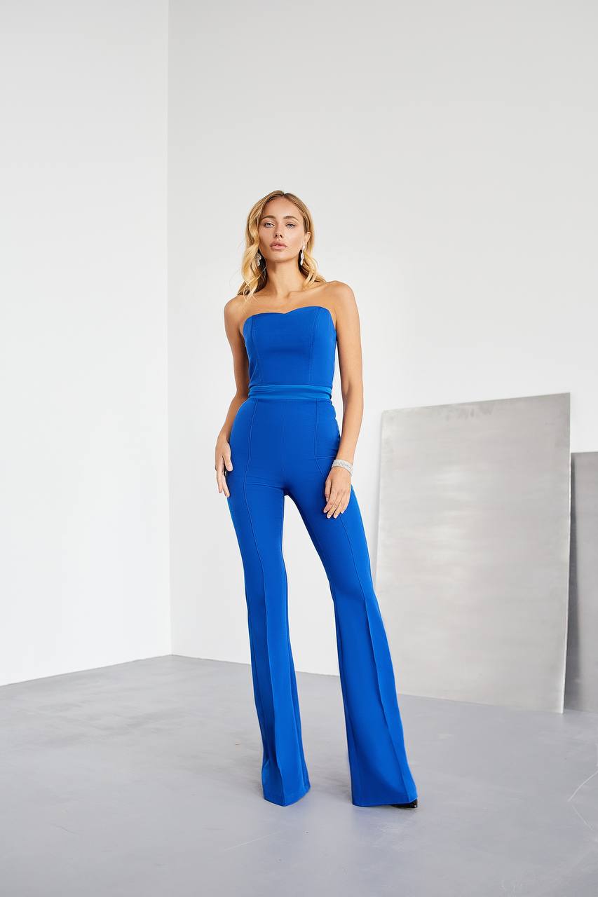 Woman wearing a blue strapless jumpsuit against a white background