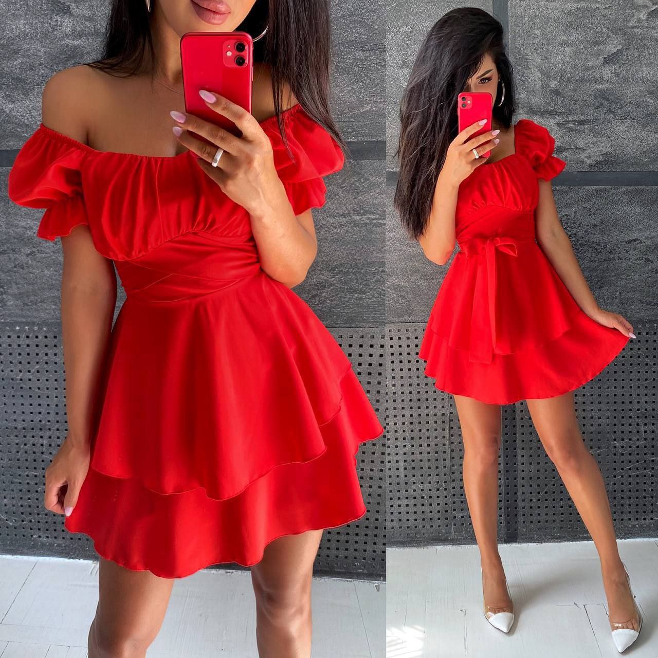 Woman wearing a red dress with ruffled sleeves and bottom, standing against a gray wall.