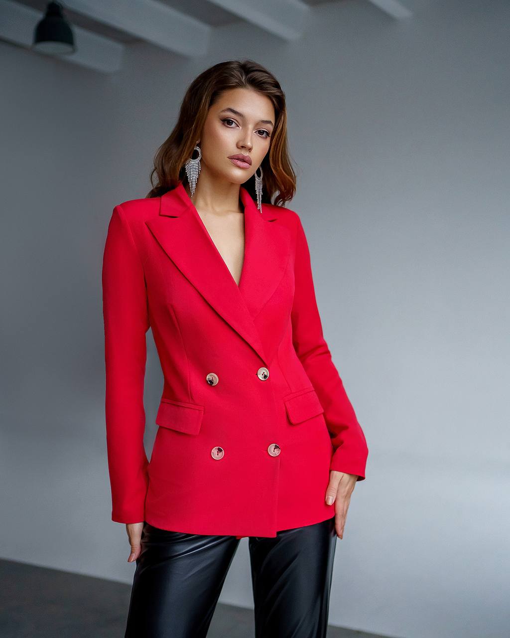 Woman wearing a red blazer with gold buttons against a gray background