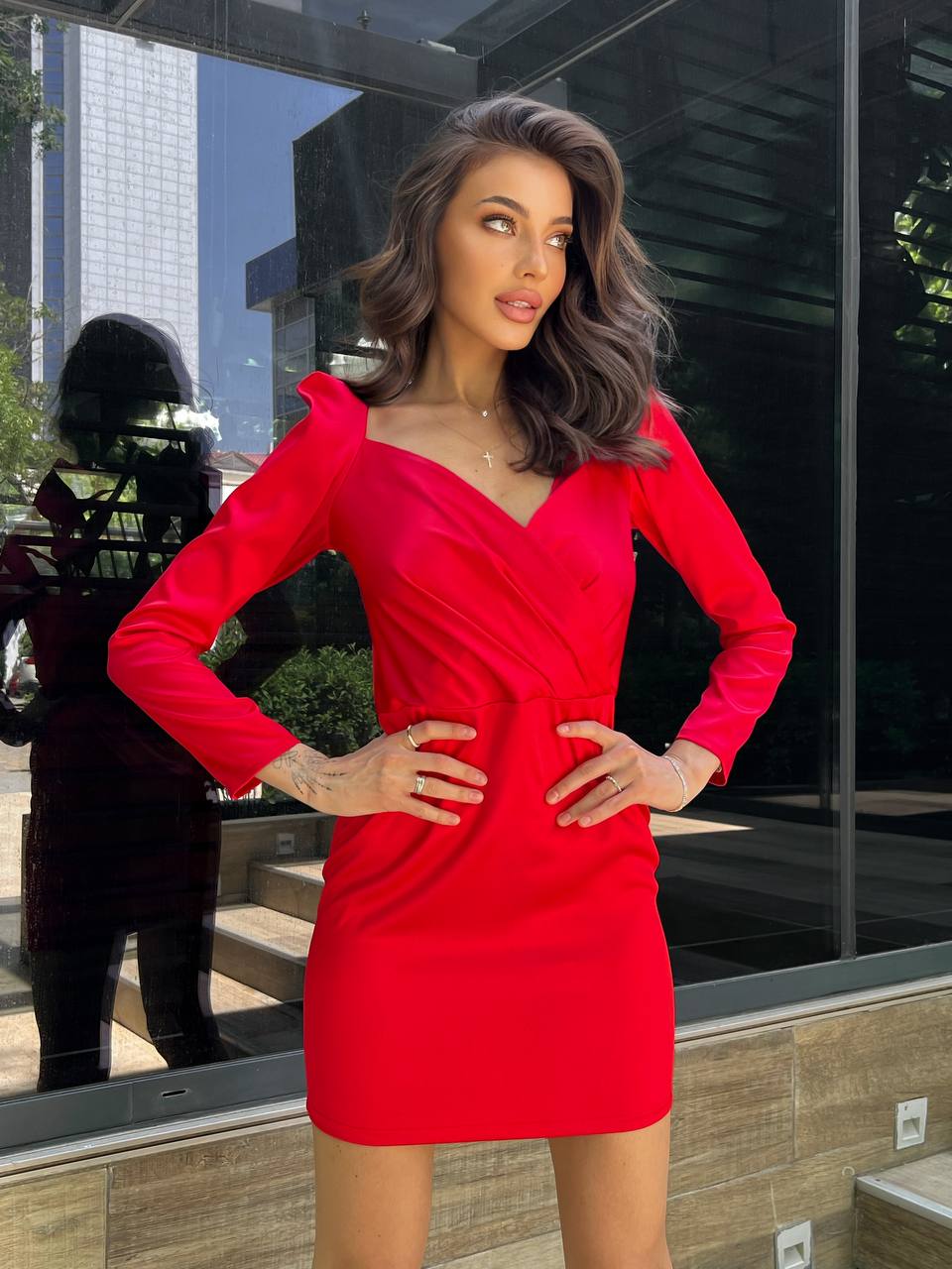 Woman in a red dress standing in front of a glass building