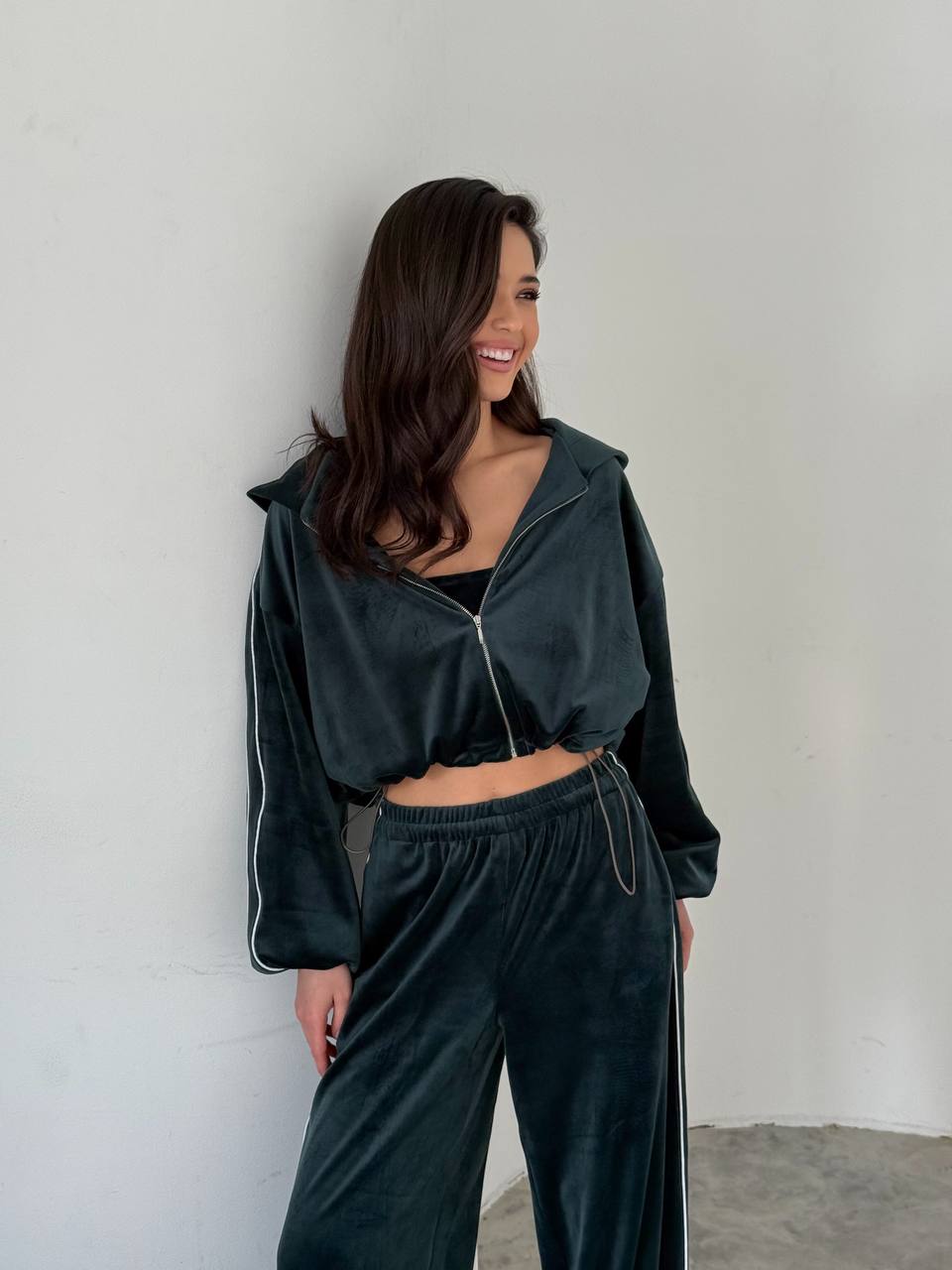 Woman wearing a dark green tracksuit against a plain background
