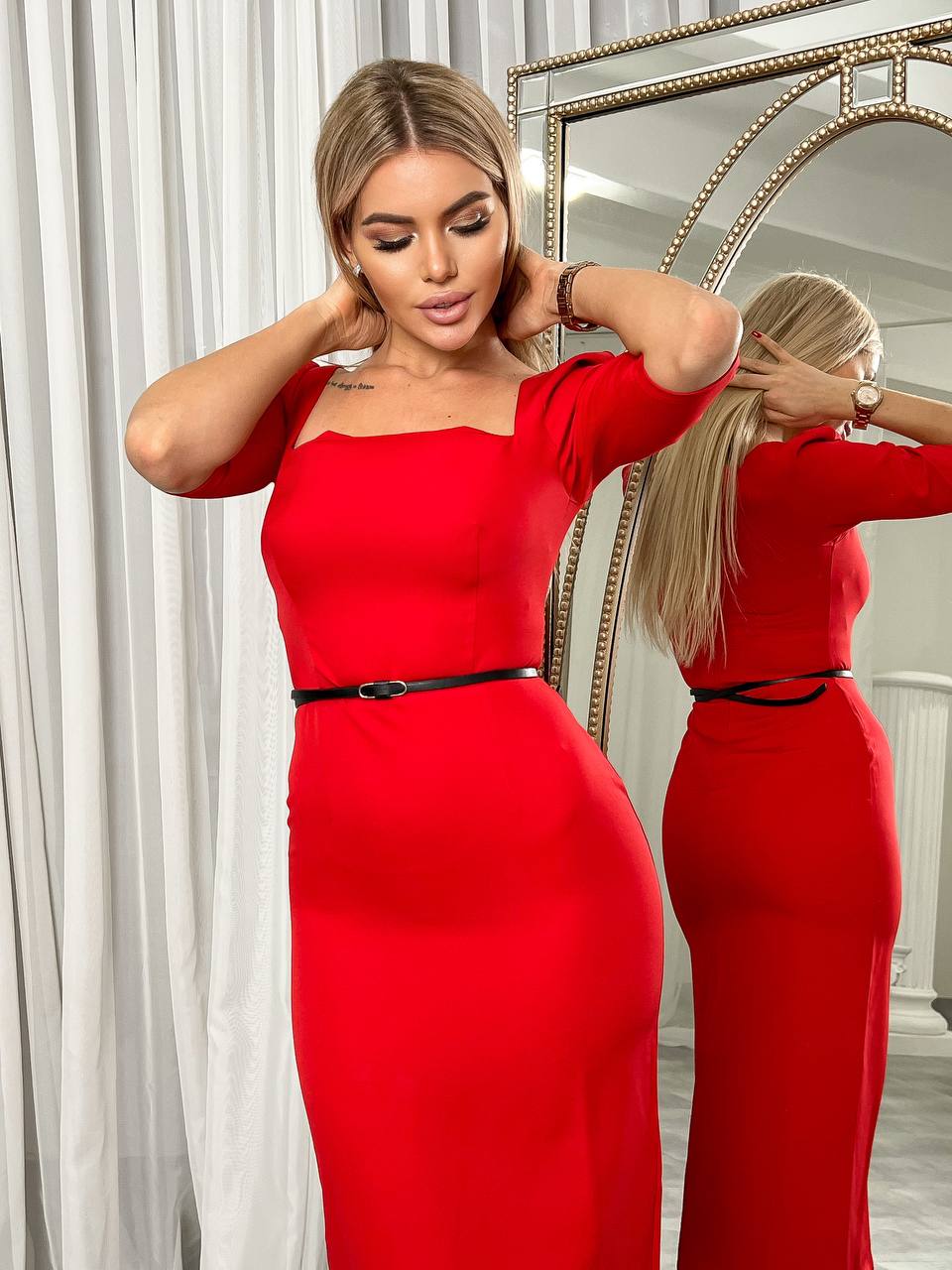 Woman in a red dress standing in front of a mirror.