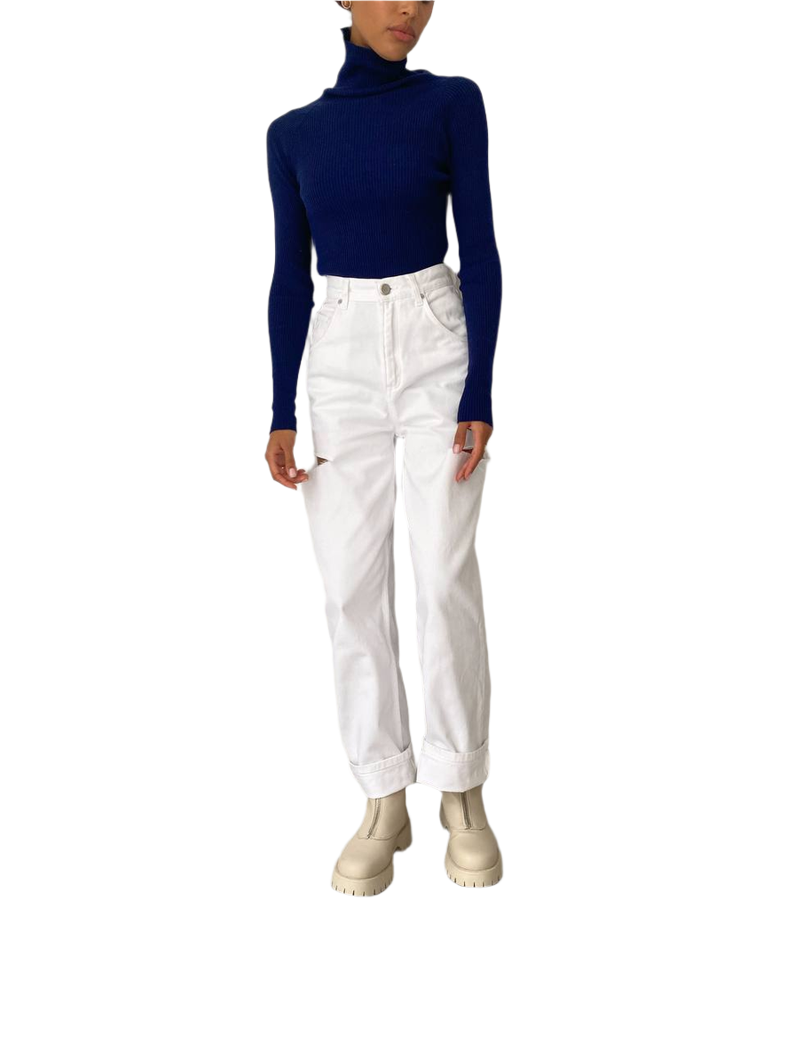 Person wearing a navy turtleneck and white pants on a white background