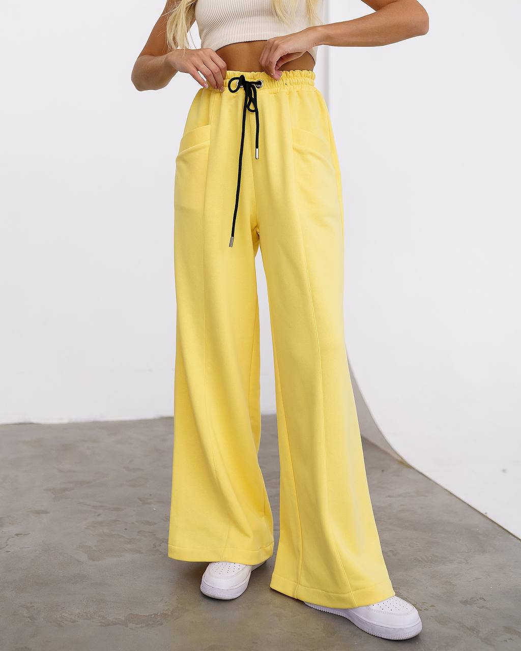 Person wearing yellow wide-leg pants with a white background