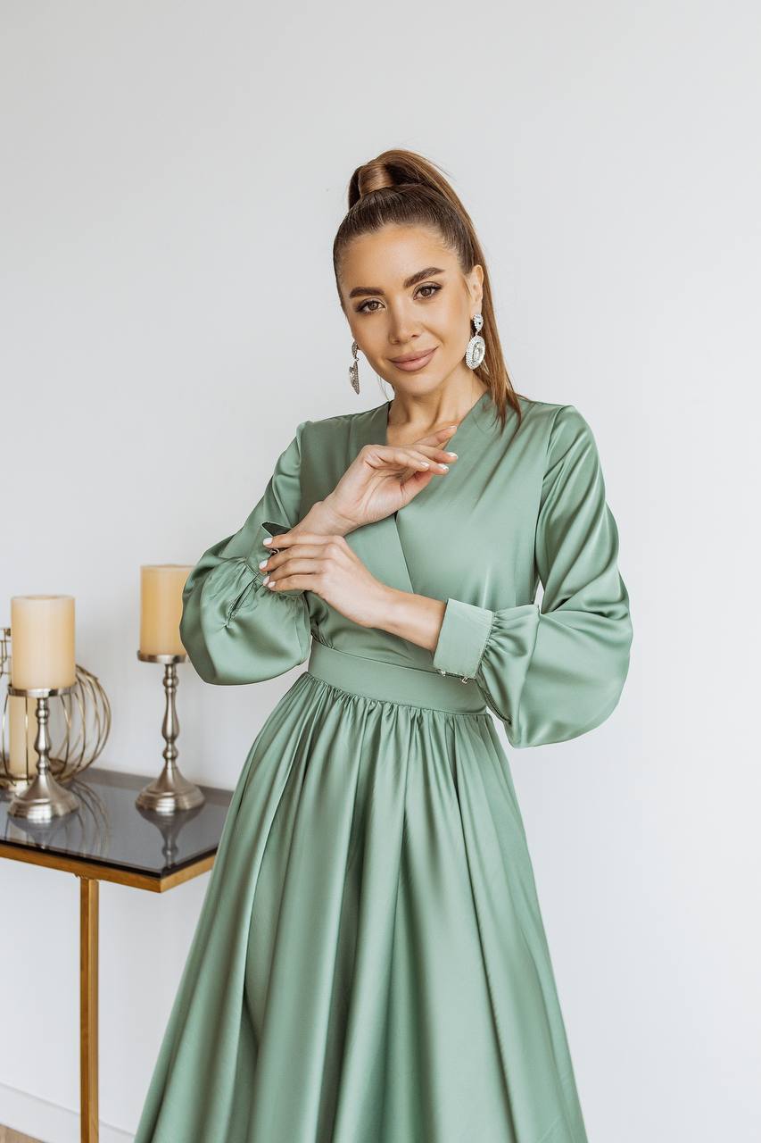 Woman wearing a green dress with candles and a lamp in the background
