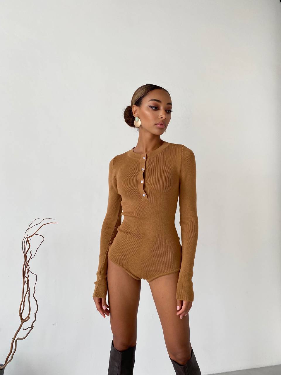 Woman wearing a brown bodysuit against a white background