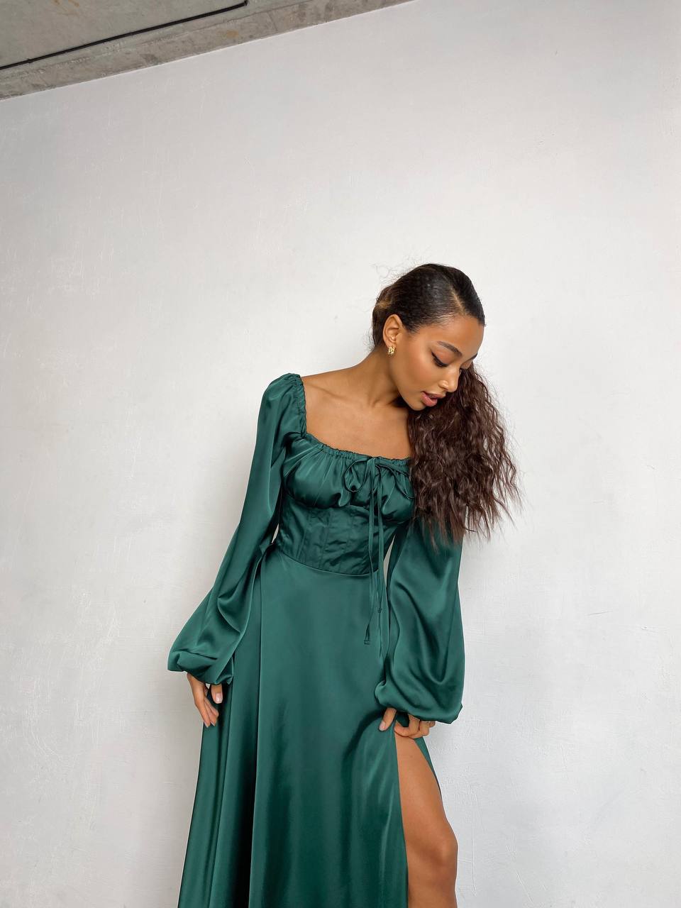 Woman wearing a green dress with long sleeves against a white background