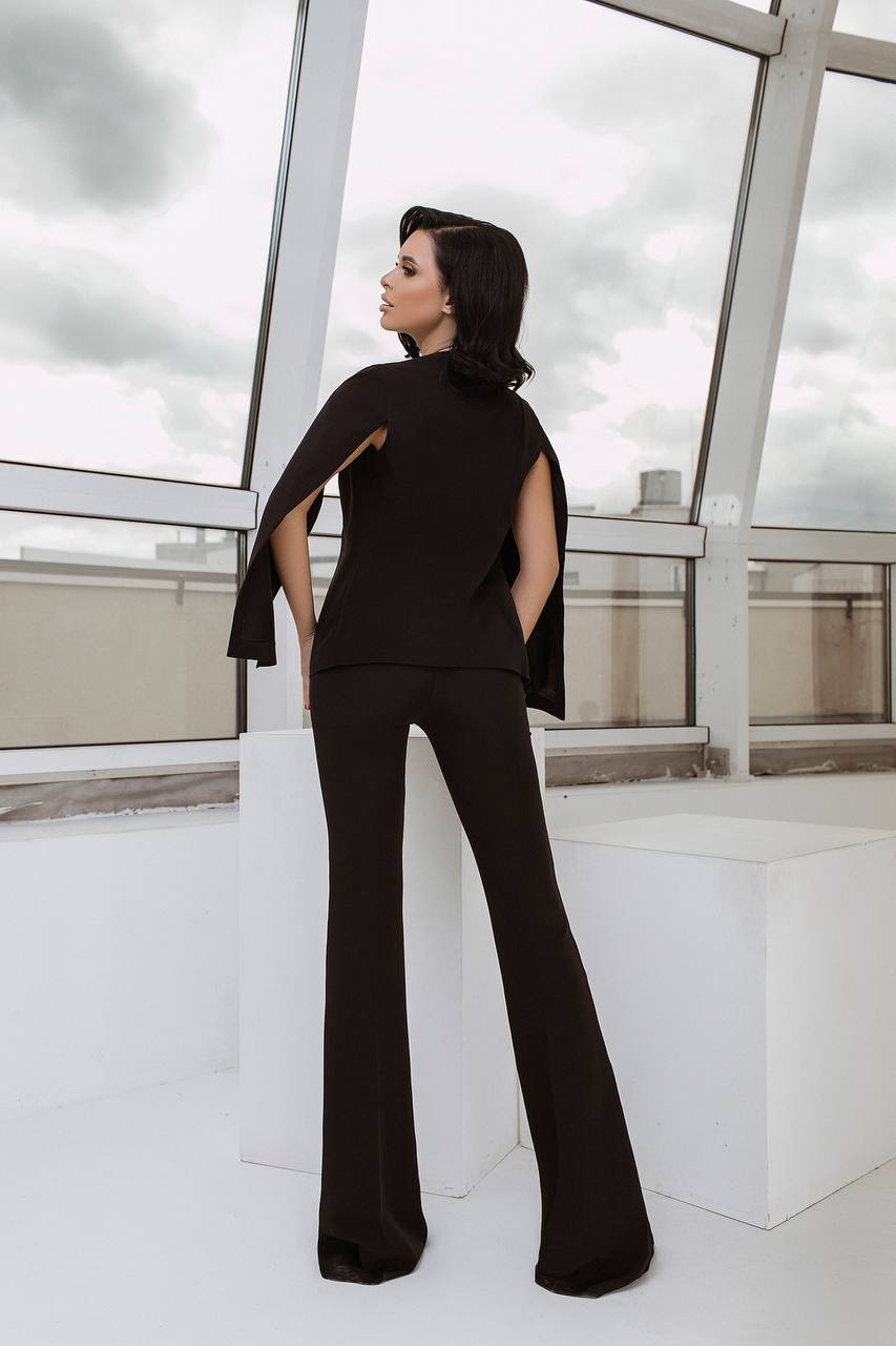 Person wearing a black outfit on a rooftop with glass walls and clouds in the background