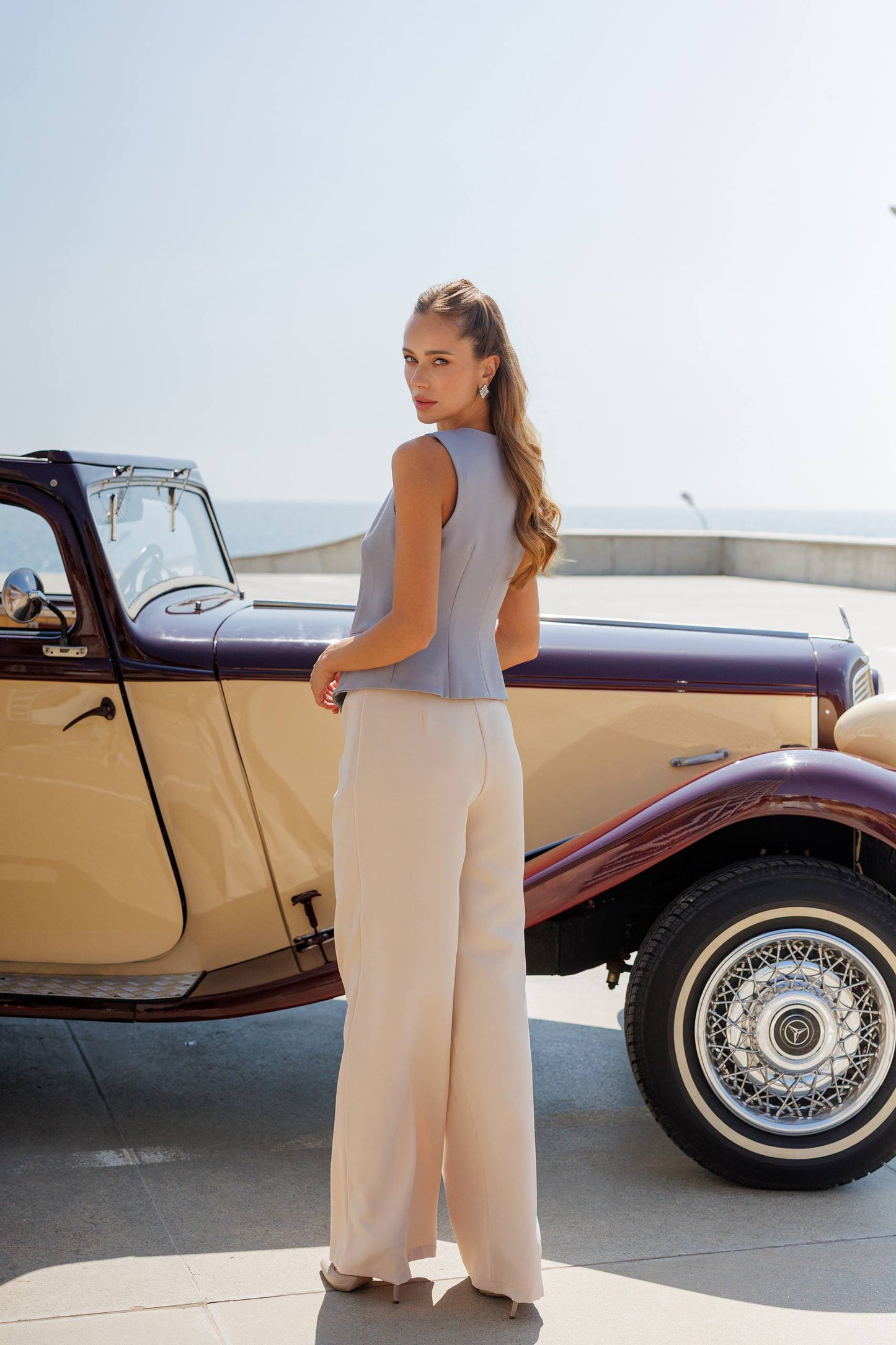 Woman standing next to a vintage car on a sunny day